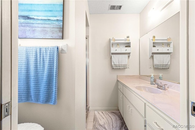 bathroom with tile patterned flooring, vanity, and a textured ceiling