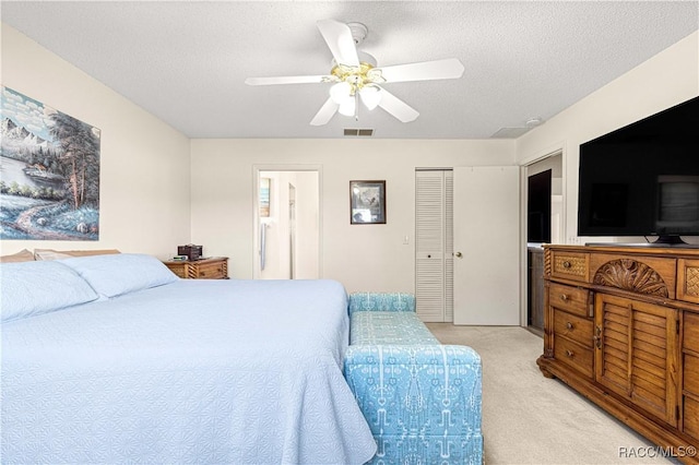 carpeted bedroom featuring ceiling fan, ensuite bathroom, and a textured ceiling