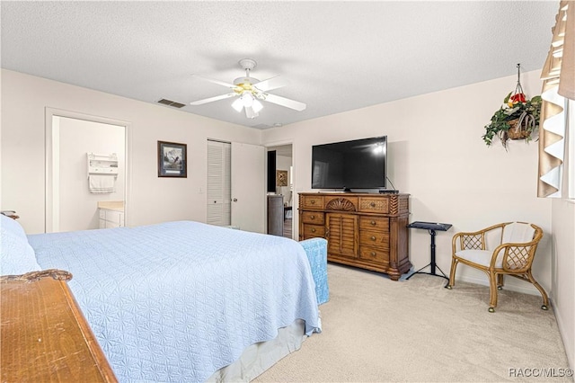 bedroom featuring ensuite bath, ceiling fan, light colored carpet, and a textured ceiling