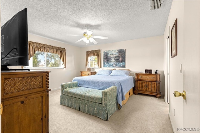 bedroom featuring ceiling fan, light carpet, and a textured ceiling