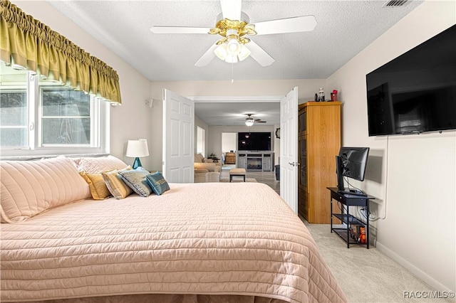 carpeted bedroom featuring ceiling fan and a textured ceiling