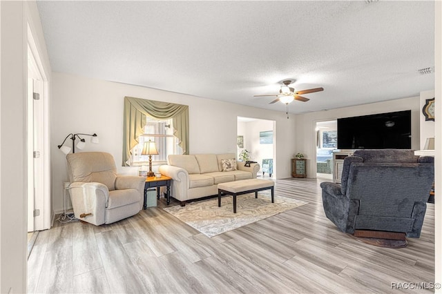 living room featuring a textured ceiling, light hardwood / wood-style floors, and ceiling fan