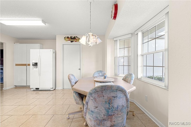 dining area with light tile patterned floors, a chandelier, and a textured ceiling