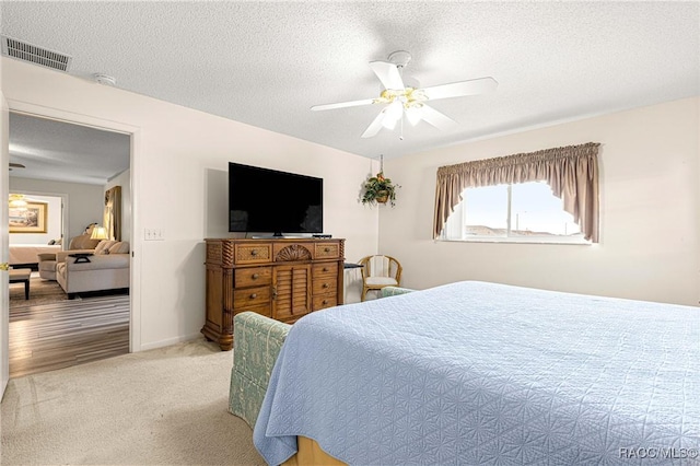 carpeted bedroom with ceiling fan and a textured ceiling