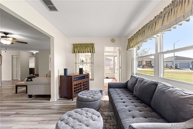 living room with ceiling fan, wood-type flooring, and a textured ceiling