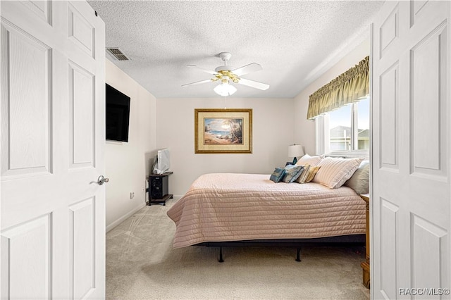 carpeted bedroom with ceiling fan and a textured ceiling