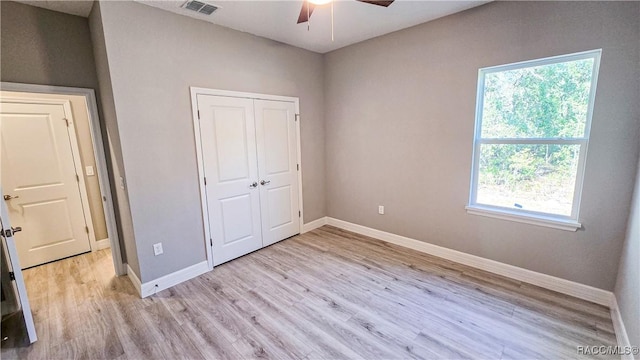 unfurnished bedroom featuring ceiling fan, a closet, and light wood-type flooring