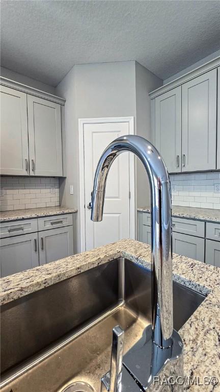 interior details with gray cabinets, tasteful backsplash, and sink