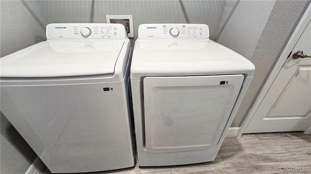 washroom with independent washer and dryer and light hardwood / wood-style floors