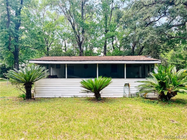 view of front of house featuring a sunroom and a front lawn