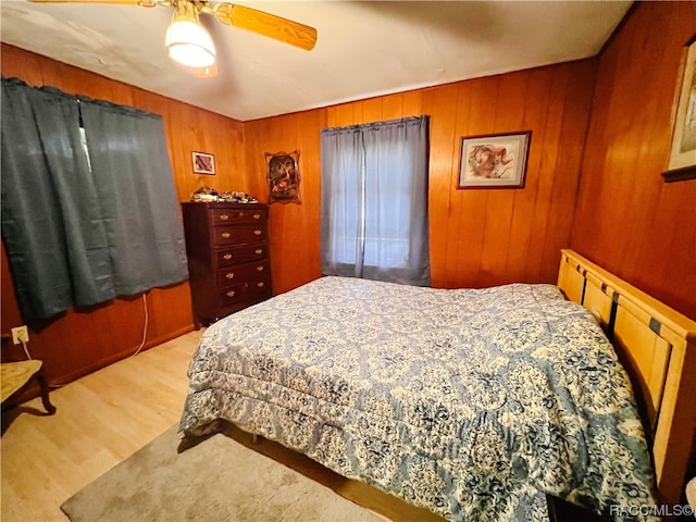 bedroom featuring light hardwood / wood-style flooring, ceiling fan, and wood walls