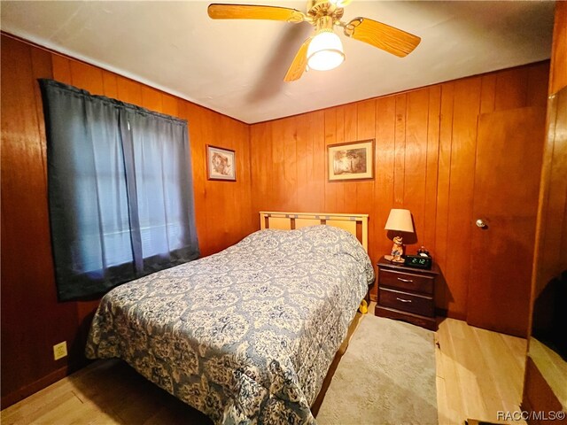 bedroom with ceiling fan and wood walls