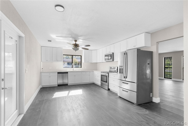 kitchen with dark wood-type flooring, sink, ceiling fan, white cabinetry, and stainless steel appliances