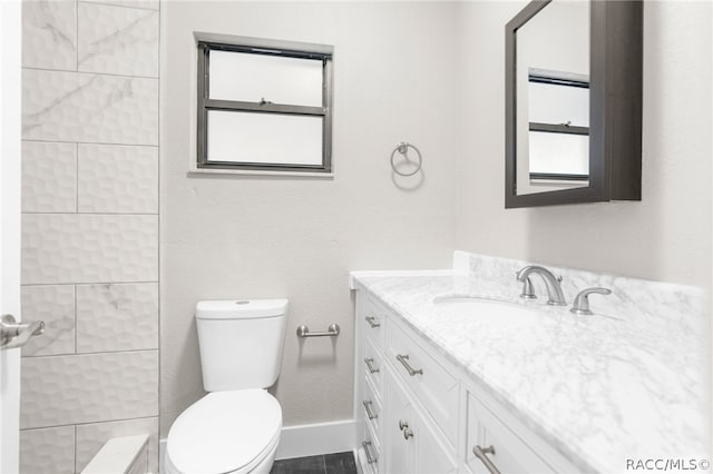 bathroom with tiled shower, vanity, and toilet