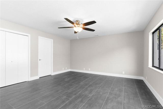 unfurnished bedroom featuring ceiling fan and two closets