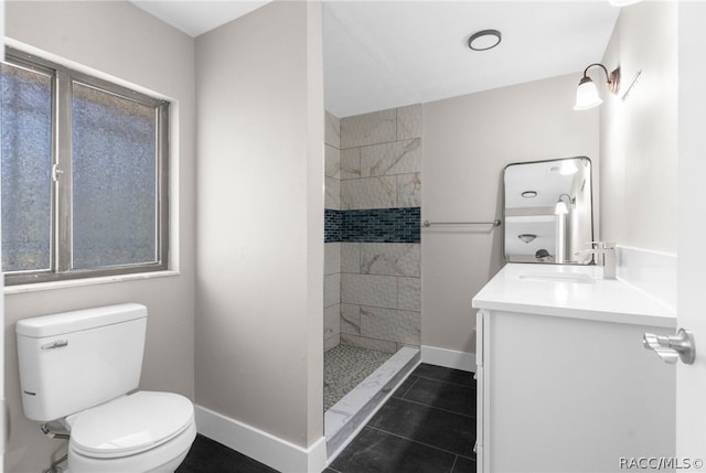 bathroom with a tile shower, vanity, toilet, and tile patterned floors