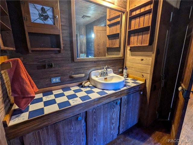 bathroom with vanity, hardwood / wood-style floors, and wood walls