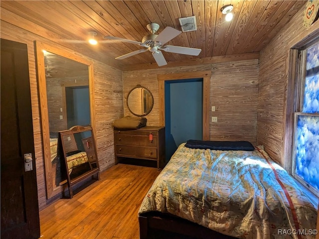 bedroom with ceiling fan, wood-type flooring, wooden walls, and wooden ceiling