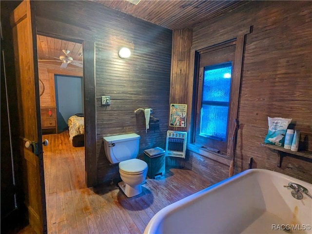 bathroom featuring a bathtub, heating unit, wood-type flooring, wooden ceiling, and toilet