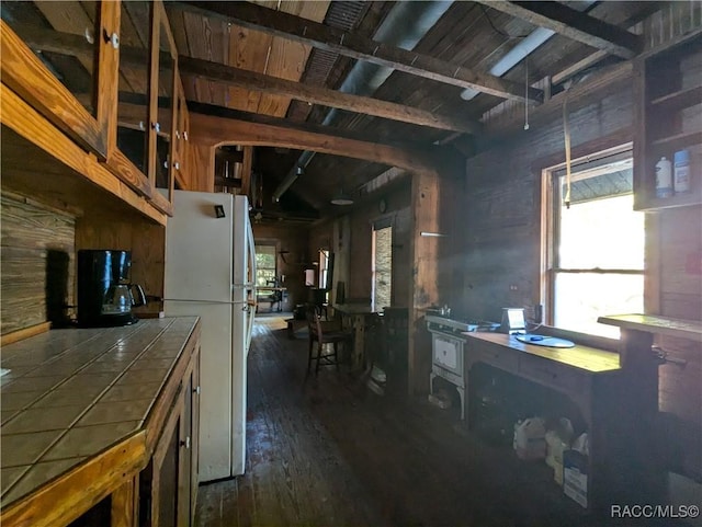 kitchen with white fridge, dark wood-type flooring, tile countertops, and wooden walls