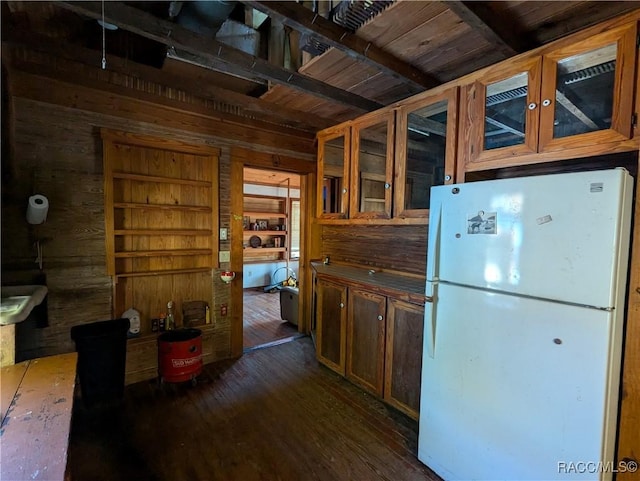 kitchen featuring dark wood-type flooring, wooden walls, built in shelves, and white fridge