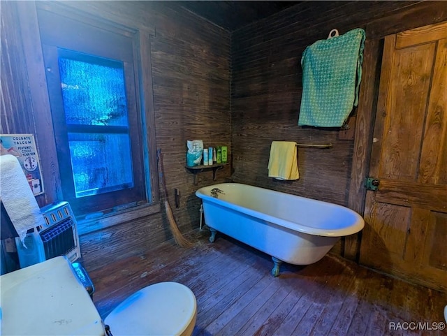 bathroom featuring a bath, hardwood / wood-style floors, toilet, and wood walls