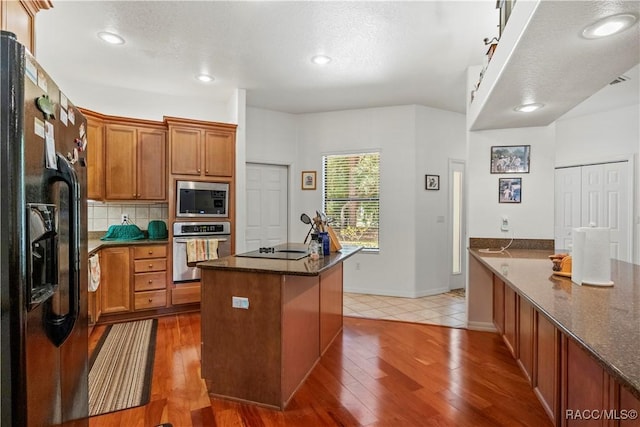 7634 N Hargrove Pt, Crystal River, FL 34428 - kitchen with black appliances, dark stone counters, light wood-type flooring, decorative backsplash, and brown cabinets