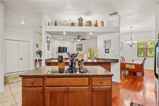 7634 N Hargrove Pt, Crystal River, FL 34428 - kitchen featuring black electric cooktop, a chandelier, brown cabinets, and dark stone countertops