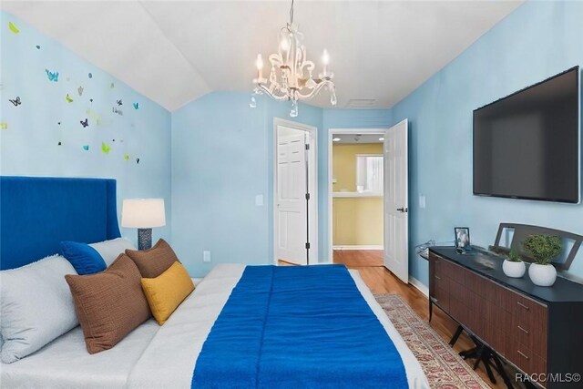 miscellaneous room with an inviting chandelier, light wood-type flooring, and vaulted ceiling