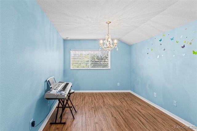 living area featuring hardwood / wood-style floors, a chandelier, and vaulted ceiling