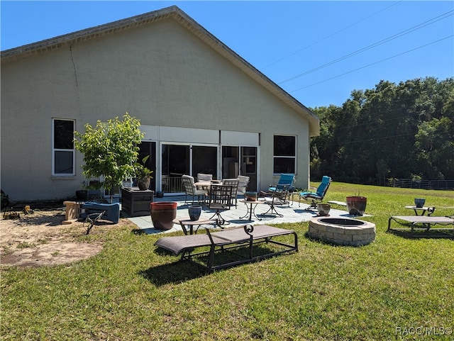 rear view of property with a patio, an outdoor fire pit, and a lawn