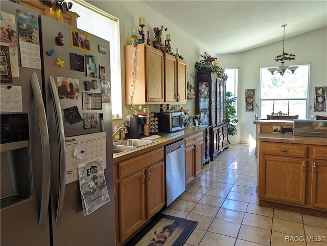 kitchen featuring appliances with stainless steel finishes, sink, pendant lighting, a chandelier, and light tile patterned flooring