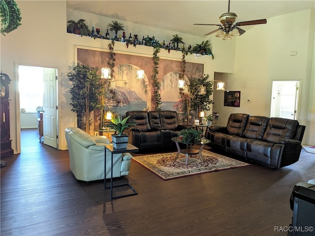 living room with ceiling fan, dark wood-type flooring, and a high ceiling