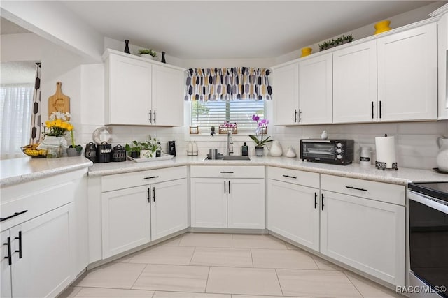 8849 SW 116th Place Rd, Ocala, FL 34481 - kitchen with a sink, stainless steel electric range, decorative backsplash, white cabinets, and light countertops