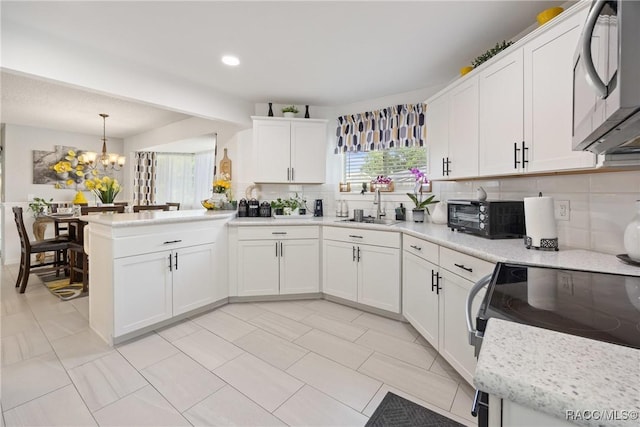 8849 SW 116th Place Rd, Ocala, FL 34481 - kitchen with decorative backsplash, a sink, light countertops, a peninsula, and a chandelier