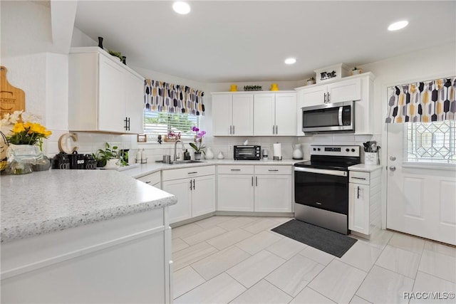 8849 SW 116th Place Rd, Ocala, FL 34481 - kitchen with appliances with stainless steel finishes, a sink, decorative backsplash, white cabinetry, and recessed lighting
