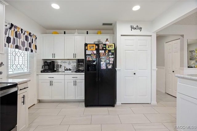 8849 SW 116th Place Rd, Ocala, FL 34481 - kitchen with black fridge, light countertops, white cabinets, range with electric stovetop, and tasteful backsplash
