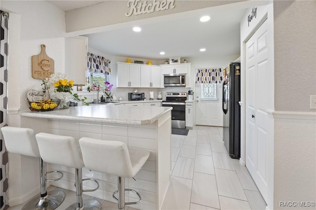 8849 SW 116th Place Rd, Ocala, FL 34481 - kitchen featuring stainless steel appliances, a sink, a peninsula, light countertops, and white cabinetry