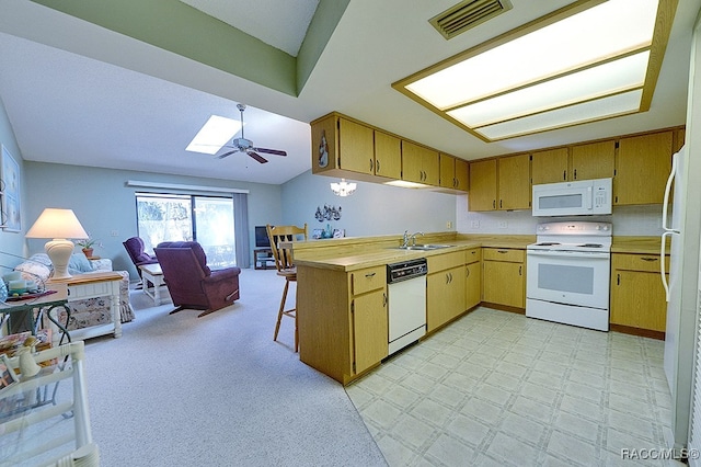 kitchen featuring kitchen peninsula, a breakfast bar, white appliances, ceiling fan, and sink