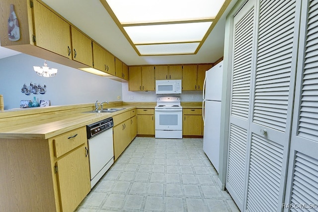 kitchen featuring white appliances, an inviting chandelier, and sink