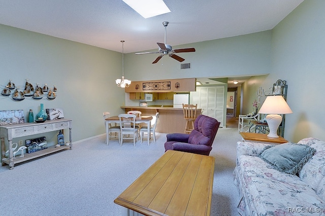 living room with carpet, ceiling fan with notable chandelier, and a skylight