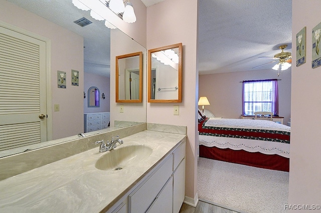 bathroom featuring a textured ceiling, vanity, hardwood / wood-style flooring, and ceiling fan