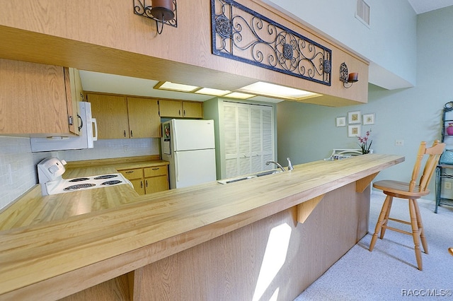 kitchen with kitchen peninsula, a breakfast bar, sink, and white appliances