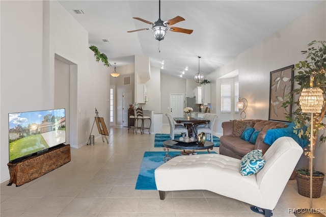 living room with ceiling fan with notable chandelier, lofted ceiling, and light tile patterned floors