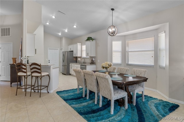 tiled dining room with sink, lofted ceiling, and a notable chandelier