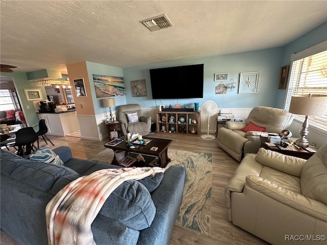 living room with a healthy amount of sunlight, light hardwood / wood-style floors, and a textured ceiling