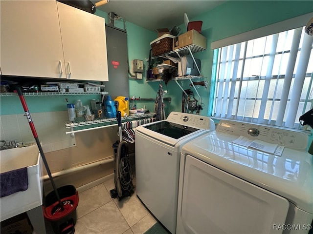 clothes washing area featuring cabinets, light tile patterned floors, and washing machine and clothes dryer