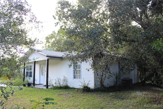 rear view of property with a yard and central air condition unit