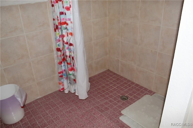 bathroom with toilet, curtained shower, and tile walls