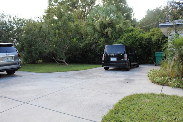 view of parking / parking lot featuring a lawn